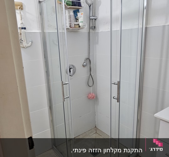 מקלחון זכוכית פינתי עם דלתות הזזה ומסגרת אלומיניום מבריקה